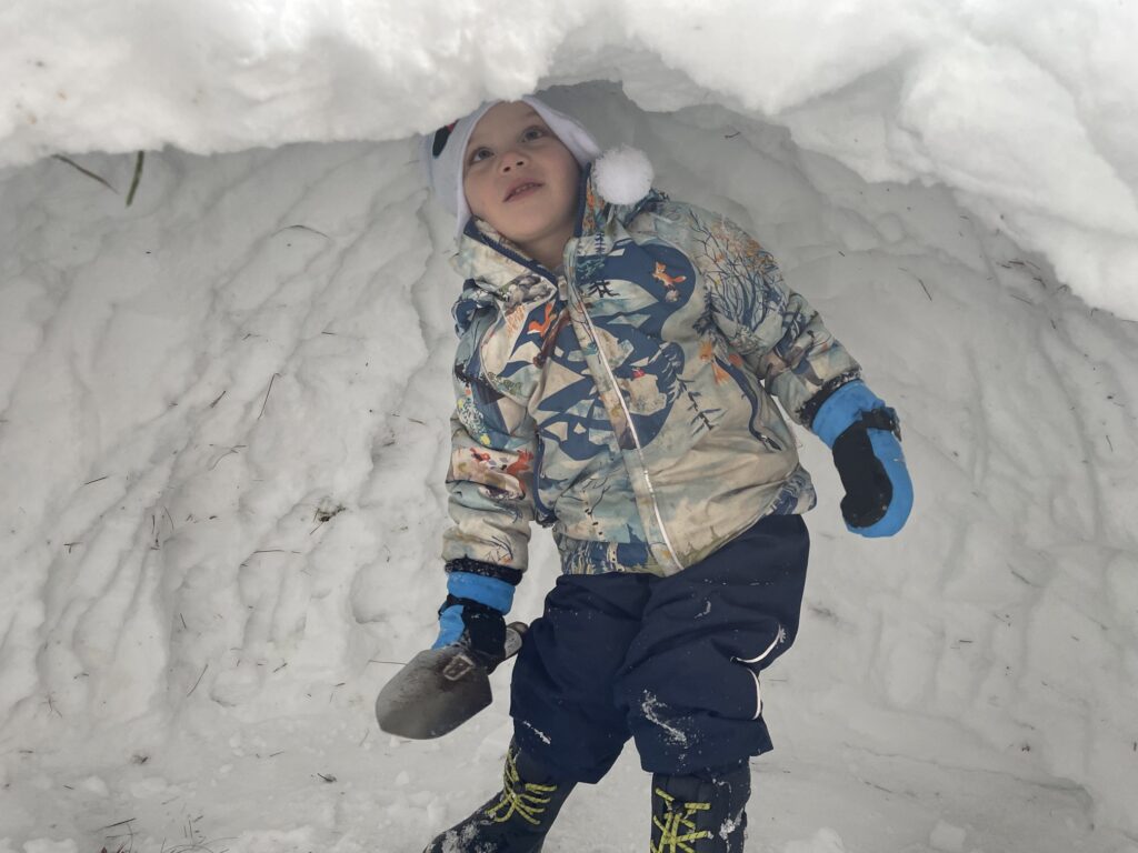 A child barely clearing the snow ceiling of the quinzhee.